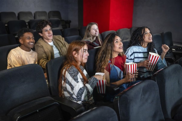 Group of excited friends enjoying a movie and eating popcorn in a cinema, sharing a fun and entertaining experience