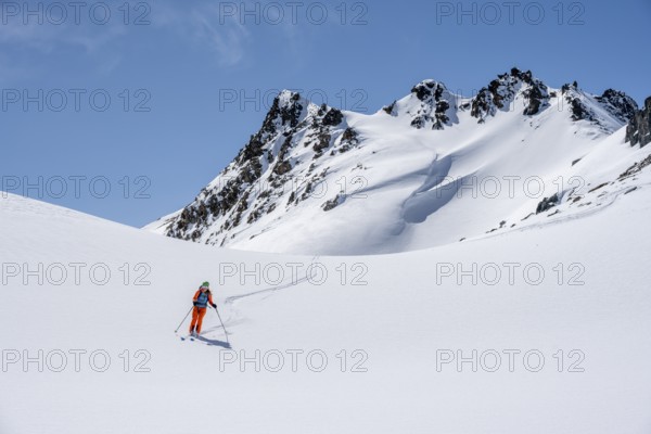 Ski tourer on the descent, minimalist winter landscape, white snow and dark mountains on the Scalettahorn, Graubünden, Switzerland, Europe