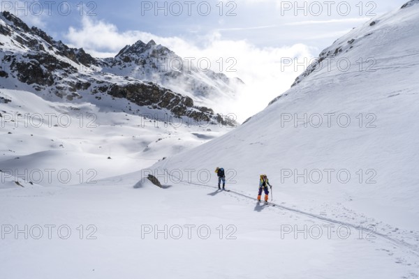 Atmospheric clouds in a wintry mountain landscape, ski tourers on the ascent to Porta d'Es-cha, Grisons Haute Route ski tour, Albula Alps, Rhaetian Alps, Grisons, Eastern Switzerland, Switzerland, Europe