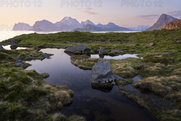 Landscape at Stornappstinden mountain. Foothills of a stream in the foreground. View of the mountains Hogskolmen, Himmeltindan, Veggen and Mannen near Haukland, Offersoykammen on the right. At night at the time of the midnight sun in good weather. Early summer. Flakstadoya, Lofoten, Norway, Europe