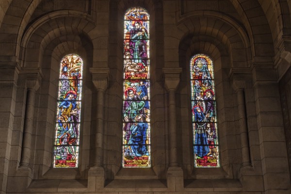 Three stained glass windows in a church, illuminated with various religious scenes, Paris