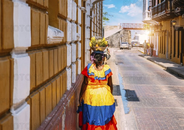 Colombia, lady in national colorful costume walking the streets of Walled City historic center of Cartagena, South America