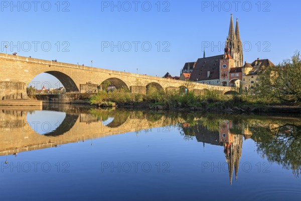 Church and bridge reflected in river, evening light, sunny, idyllic, Regensburg Cathedral and stone bridge, Regensburg, Danube, Bavaria, Germany, Europe