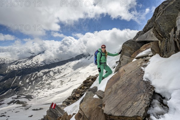 Mountaineer on a rocky hiking trail with snow, mountain panorama with snow-covered mountain peaks in the background, Berliner Höhenweg, Zillertal Alps, Tyrol, Austria, Europe