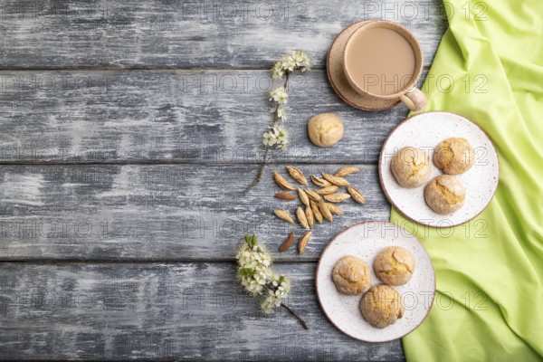 Almond cookies and a cup of coffee on a gray wooden background and green linen textile. Top view, flat lay, copy space