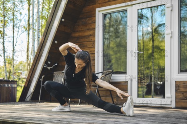 Sporty woman doing side slopes on terrace of bungalow