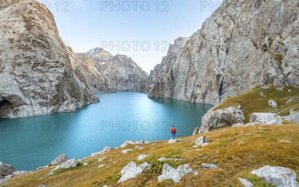 Young man at the turquoise mountain lake Kol Suu with rocky steep mountains, Kol Suu Lake, Sary Beles Mountains, Naryn Province, Kyrgyzstan, Asia