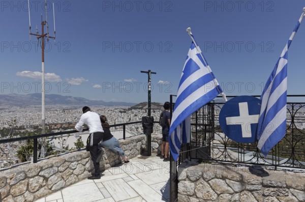 Lycabettus, Lykavittos viewing terrace with Greek flags, couple looking at city panorama, Athens, Greece, Europe