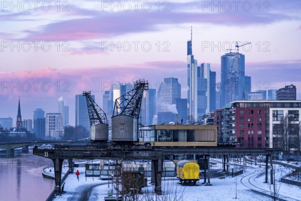 The skyline of Frankfurt am Main, skyscrapers of the banking district, historic harbour cranes at the Wesel shipyard, wintry morning, Hesse, Germany, Europe
