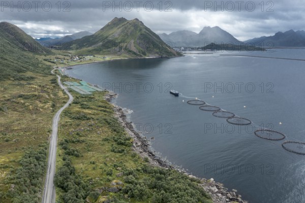 Aerial view of a salmon farm, rainy weather, grey sky, village Myre in the back, Vesteralen islands, Norway, Europe