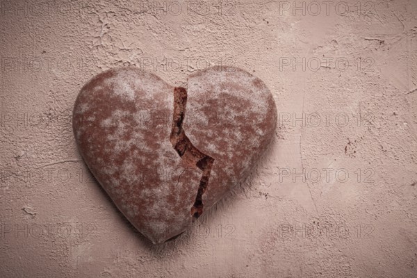 Glazed chocolate gingerbread, heart-shaped, top view, a broken heart, close-up, on beige background, no people