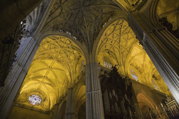 Architectural details on ceiling and stained glass rose window in Interior of The Cathedral of Saint Mary of the See or Seville Cathedral, Seville, Spain, Europe