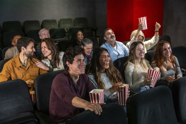 People of different ages and ethnicities are laughing and having fun while watching a movie at the cinema, eating popcorn