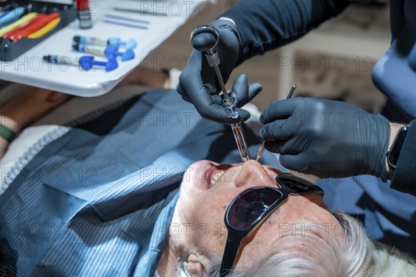 Dentist wearing black gloves injecting anesthesia to senior woman patient before dental procedure in a modern dental clinic