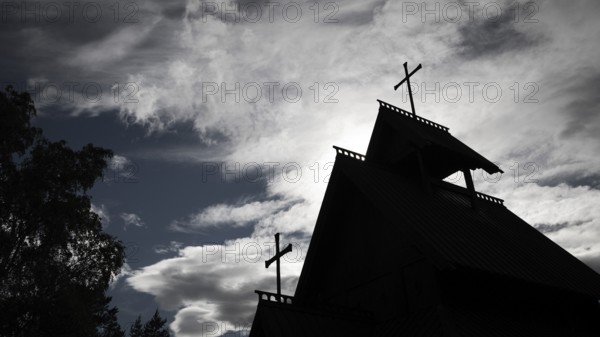 Silhouette of a church with two crosses against a dramatic cloudy sky, backdrop Kristin Lavranstochter film, Jørundgard Middelaldersenter, Olavsweg or Olavsleden, Sel municipality, Gudbrandsdalen, Norway, Europe