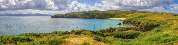 Panoramic view of a picturesque coastal landscape with cliffs, green grass and calm sea under a cloudy sky, Silver Strand