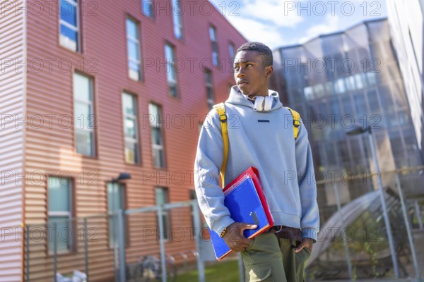 Confident african student wearing hoodie and urban clothes standing outside the university