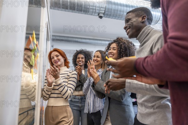Side view of multi-ethnic group of colleagues applauding after a successful brainstorming process in a coworking