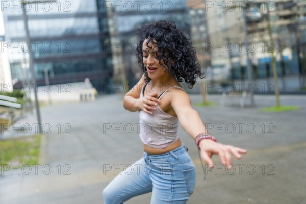 Curly haired woman dancing to lively latin music in an urban city center, soaking up the sun and radiating joy on a vibrant day