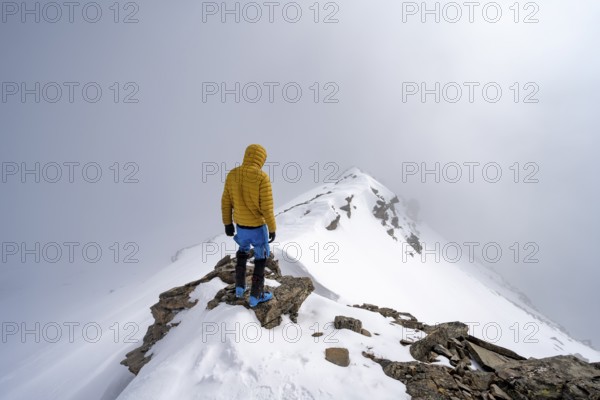 Ski tourer on the cloudy summit of Kesch Pitschen, Bündner Haute Route ski tour, Albula Alps, Rhaetian Alps, Grisons, Eastern Switzerland, Switzerland, Europe