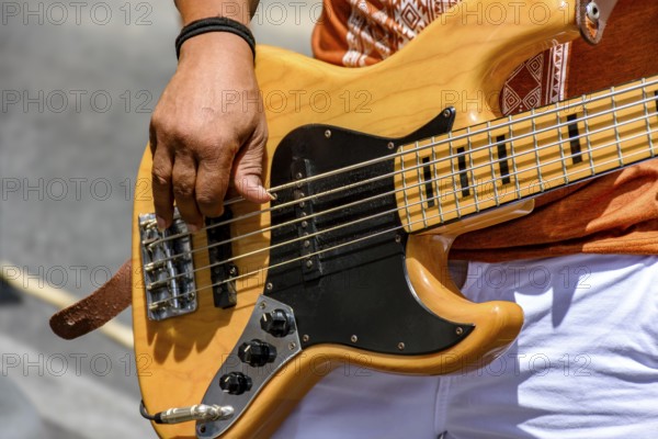 Hands playing an electric bass guitar on the street in a sunny day, Minas Gerais, Brazil, South America