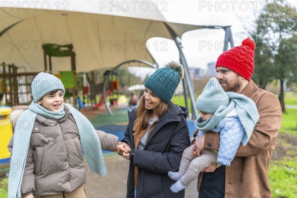 Smiling family bundled in warm winter clothes, enjoying a joyful day together at the playground, creating cherished memories outdoors