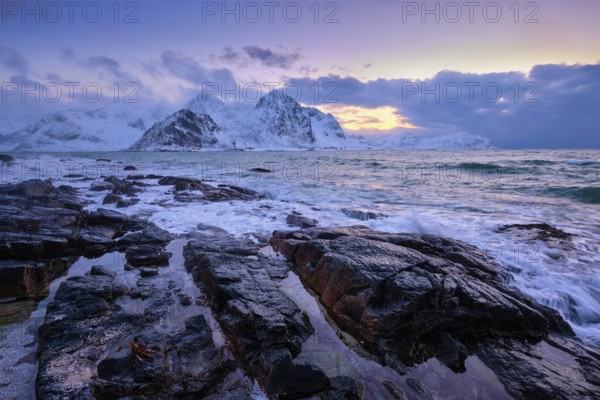 Beach of Norwegian sea on rocky coast in fjord on sunset in winter. Vareid beach, Lofoten islands, Norway, Europe