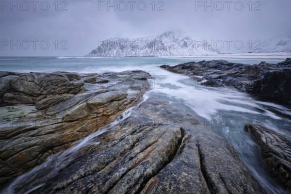 Waves and rocks on coast of Norwegian sea in fjord. Skagsanden beach, Flakstad, Lofoten islands, Norway. Long exposure motion blur