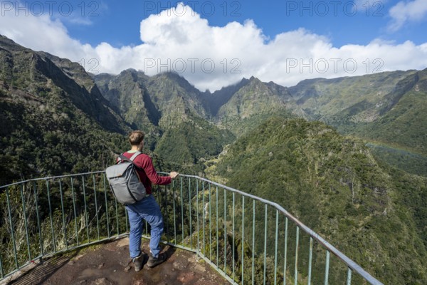 Tourist at a viewpoint, view from the Miradouro dos Balcões, densely overgrown steep mountains, green mountain landscape, mountain valley Ribeira da Metade and the central mountains, Madeira, Portugal, Europe