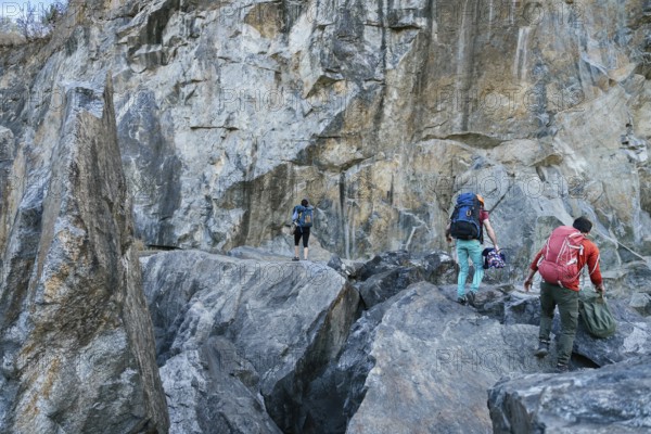 Climbers preparing for ascent. Three male female persons walking on the rocks. Extreme outdoor sport