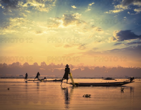 Myanmar travel attraction landmark, traditional Burmese fishermen sihouettes at Inle lake on sunset, Myanmar famous for their distinctive one legged rowing style