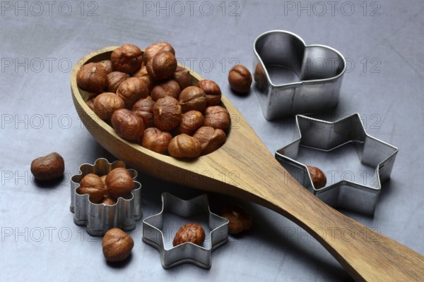 Wooden ladle with hazelnuts, cookie cutters, baking ingredient