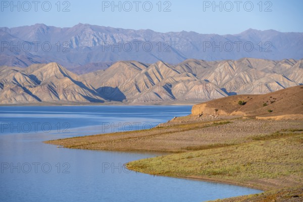 Blue Toktogul reservoir between dry mountain landscape, hilly mountains in the evening light, Jalalabad region, Kyrgyzstan, Asia