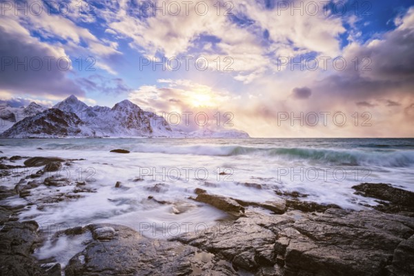 Beach of Norwegian sea on rocky coast in fjord on sunset in winter. Vareid beach, Lofoten islands, Norway, Europe