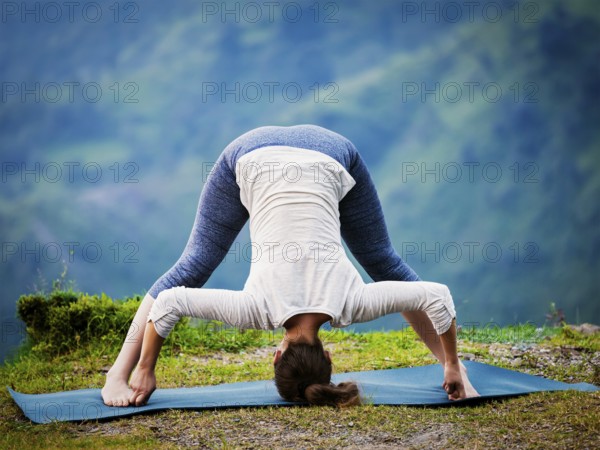 Yoga exercise outdoors, woman doing Ashtanga Vinyasa Yoga asana Prasarita padottanasana D, wide legged forward bend pose outdoors. Vintage retro effect filtered hipster style image