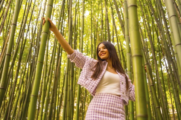 Young caucasian girl with a pink skirt in a bamboo forest. Enjoying the summer holidays in a tropical climate, walking in the forest grabbing the bamboo trunks
