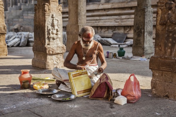 MADURAI, INDIA, FEBRUARY 16, 2013: Indian brahmin (traditional Hindu society) priest with donation in famous Meenakshi Amman Temple, historic Hindu temple located in temple city Madurai