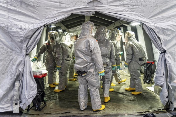 Decontamination of injured persons after an assumed accident involving hazardous substances, fire brigade and aid organisations practise setting up and operating a decontamination station, injured persons are sighted and then washed in a special shower tent to remove possible hazardous substances and chemicals in order to avoid further injuries, the emergency services wear special, ventilated protective suits, large-scale exercise by the Essen fire brigade