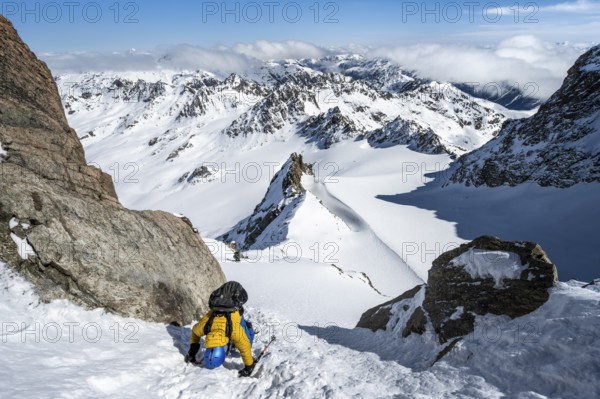 Mountaineer with ice axe and crampons, ascent through steep snowfield to Piz Kesch or Piz d'Es-cha in winter, view of mountain panorama with Vadret da Porchabella glacier, Albula Alps, Rhaetian Alps, Grisons, Eastern Switzerland, Switzerland, Europe