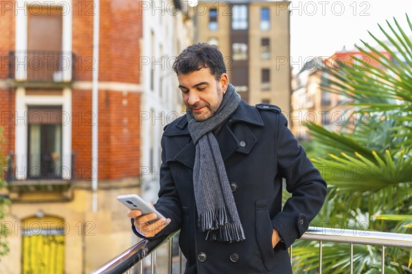 Three quarter length portrait of a caucasian adult casual businessman using phone standing in a city viewpoint
