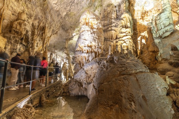 Tourists observing the magnificent stalactites and stalagmites formations inside postojna cave, a famous tourist attraction in slovenia