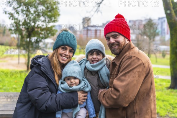 Smiling family bundled in warm winter clothes, enjoying a cheerful day outdoors in a city park, surrounded by nature and joy