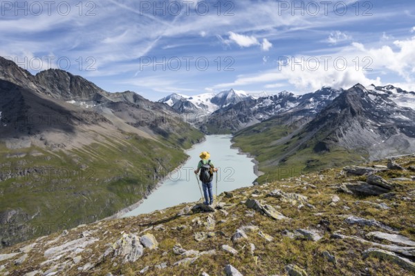 Mountaineer on the summit of Mont de la Blana, view of a blue mountain lake, Lac des Dix reservoir, behind mountain peak Mont Blanc de Cheilon with glacier, Hérménence, Valais Alps, Valais, Switzerland, Europe