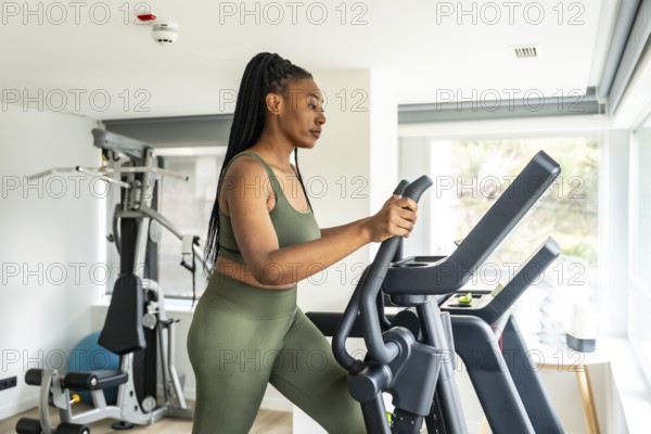 Businesswoman exercising on elliptical cross trainer in hotel gym, maintaining healthy lifestyle during business trip