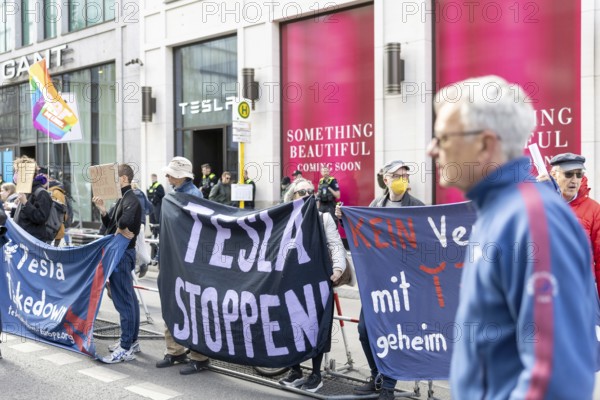 Berlin, Germany - 5 April 2025: People demonstrate in front of a Tesla shop in Berlin against Tesla owner Elon Musk during an international day of action under the banner Tesla Takedown. Banner Stop Tesla!