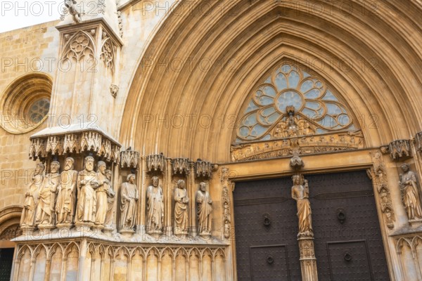 Statues of saints decorating the richly adorned main entrance of tarragona cathedral, a stunning example of gothic and romanesque architecture