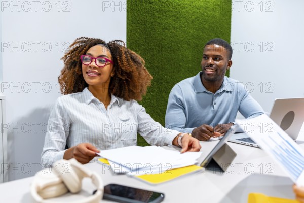 Two managers are cooperating in a modern coworking office, analyzing financial reports and discussing company strategies