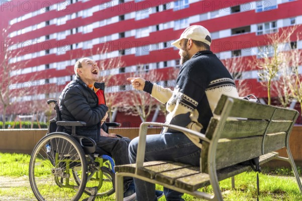 Two men enjoying time together in urban park, one using wheelchair, demonstrating inclusion and friendship