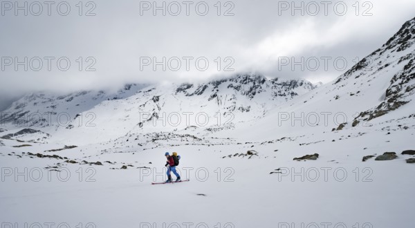 Ski tourers in a wintry mountain landscape with cloudy mountain peaks, ascent to Piz Laviner, Grisons Haute Route, Albula Alps, Rhaetian Alps, Grisons, Eastern Switzerland, Switzerland, Europe
