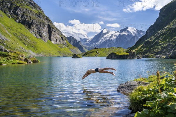 Man taking a header, cooling off while swimming in the mountain lake Lac de Louvie, behind the summit of the Grand Combin, Val de Bagnes, Valais, Switzerland, Europe